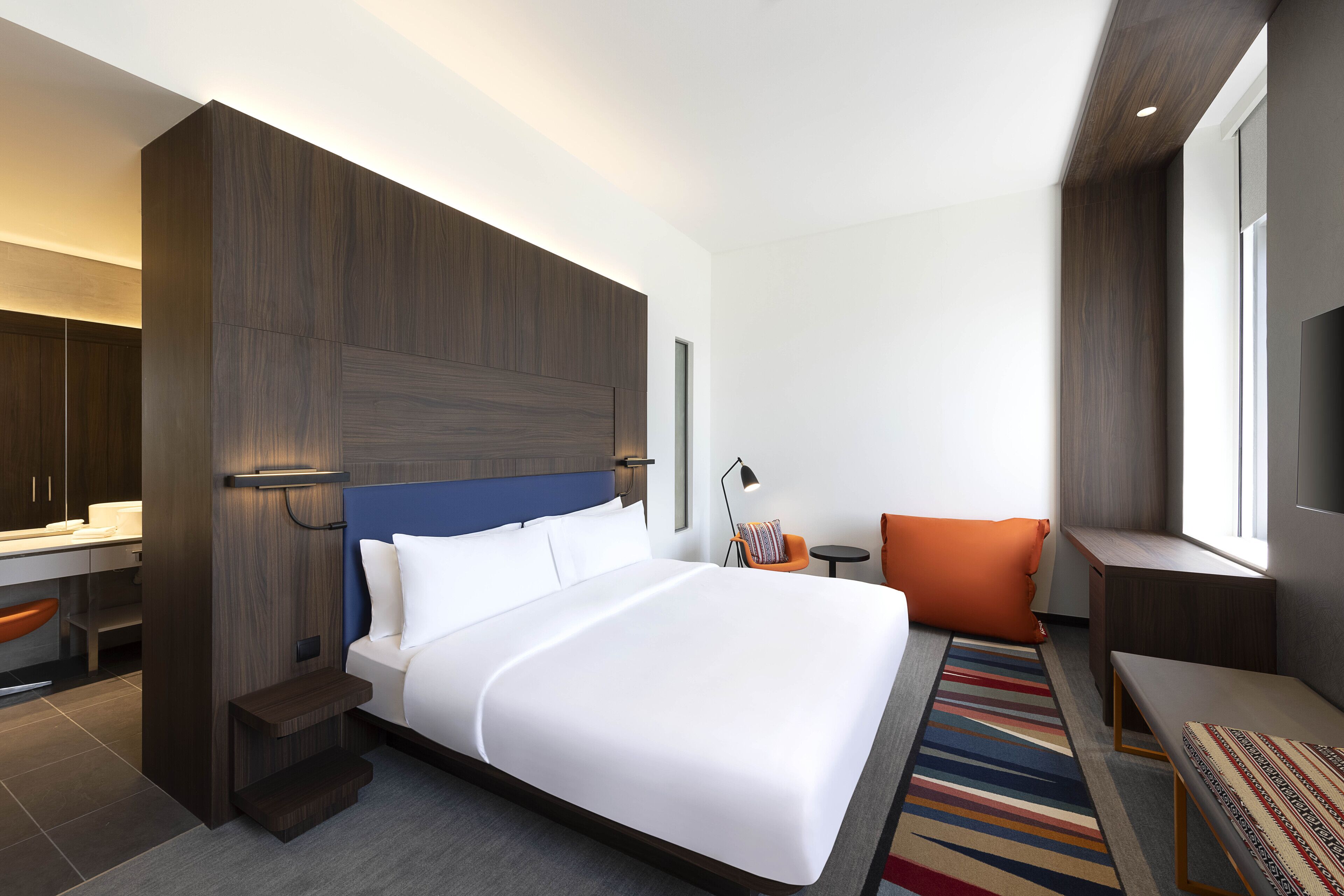 Una habitación de hotel moderna con una cama grande, un escritorio y una zona de estar.