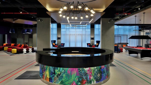 A modern lobby with a pool table, comfortable seating, and a large digital display. - Aloft by Marriott Dubai Airport (Dubai)
