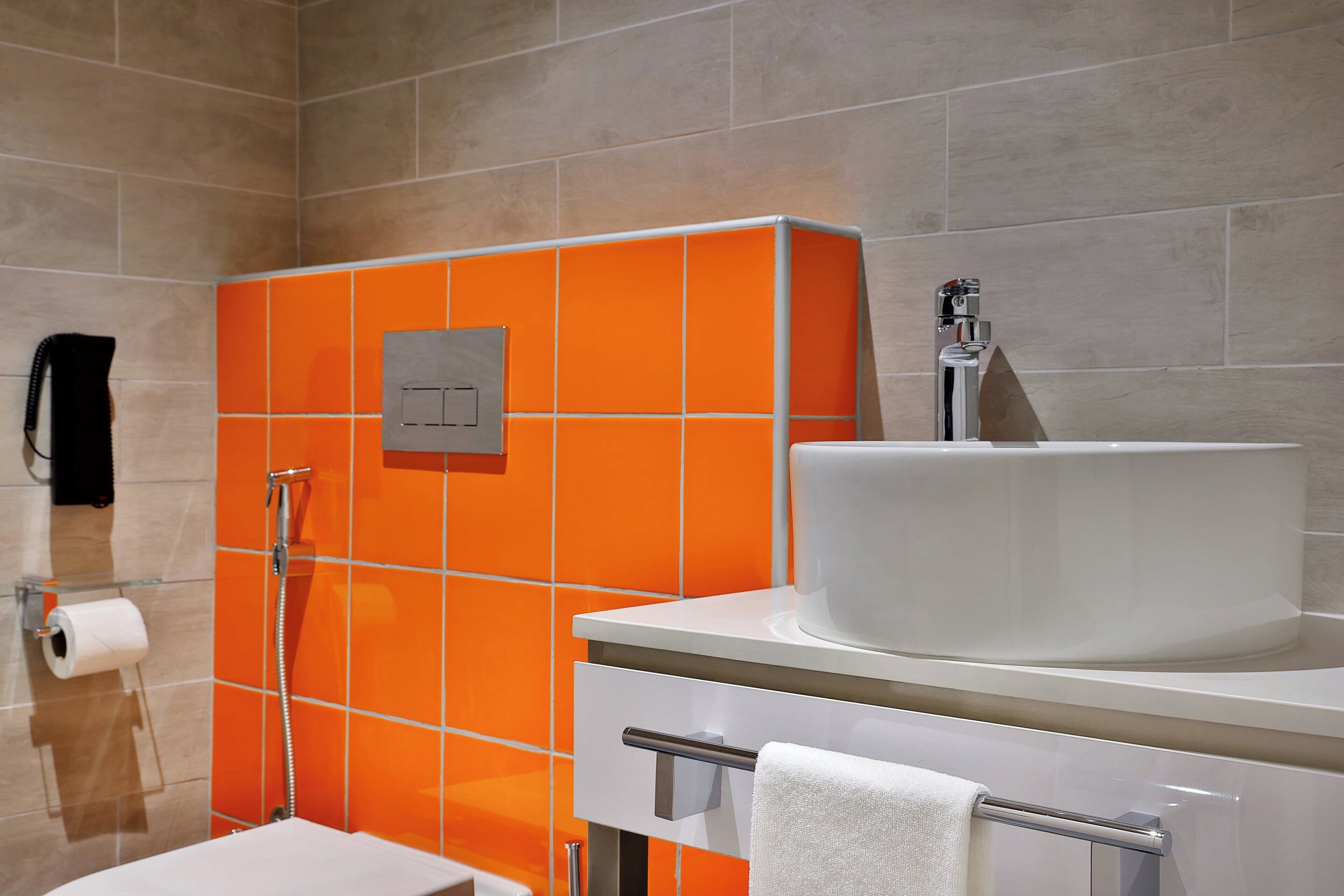 Ein Badezimmer mit weißem Waschbecken, orangefarbenen Fliesen, einem Handtuchhalter und einem Toilettenpapierrollenhalter.