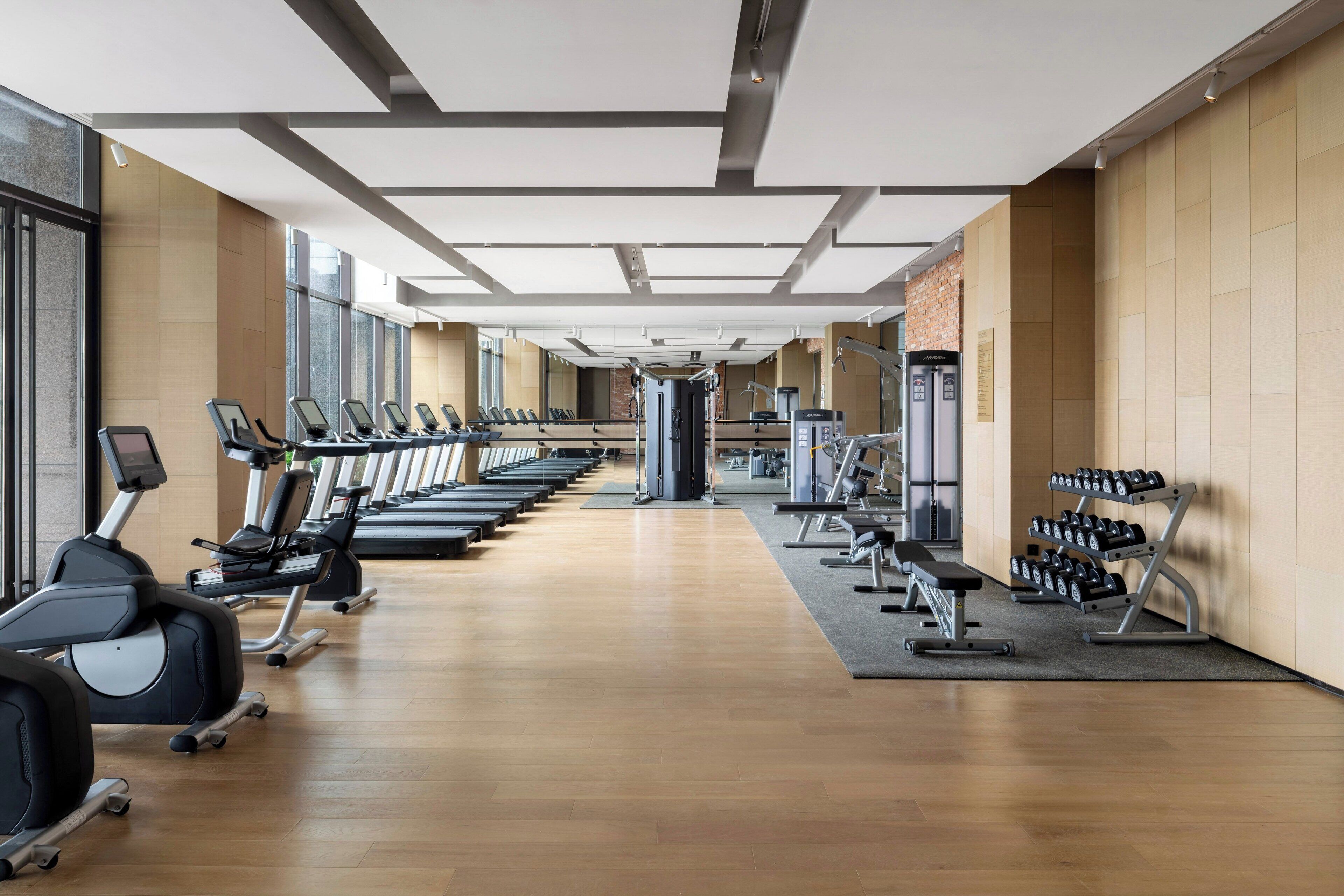 A gym with treadmills, elliptical machines, and weightlifting equipment.