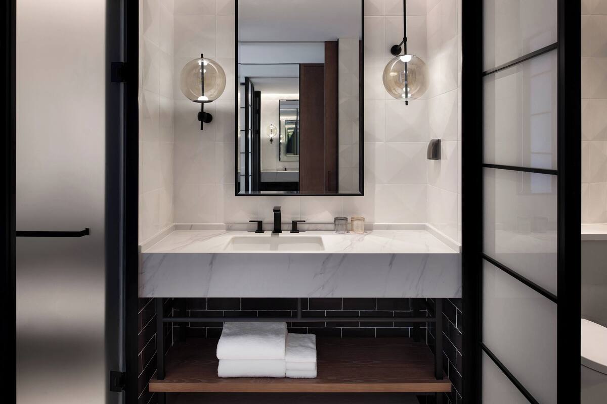 A modern bathroom with a double sink, a large mirror, and two wall-mounted light fixtures.