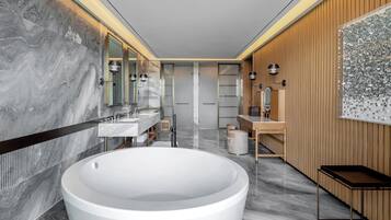 A modern bathroom with a large freestanding bathtub, dual sinks, and a vanity with a mirror.