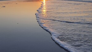 A beach at sunset with calm waves and a clear sky. - Eco Indigo (Dunbar)
