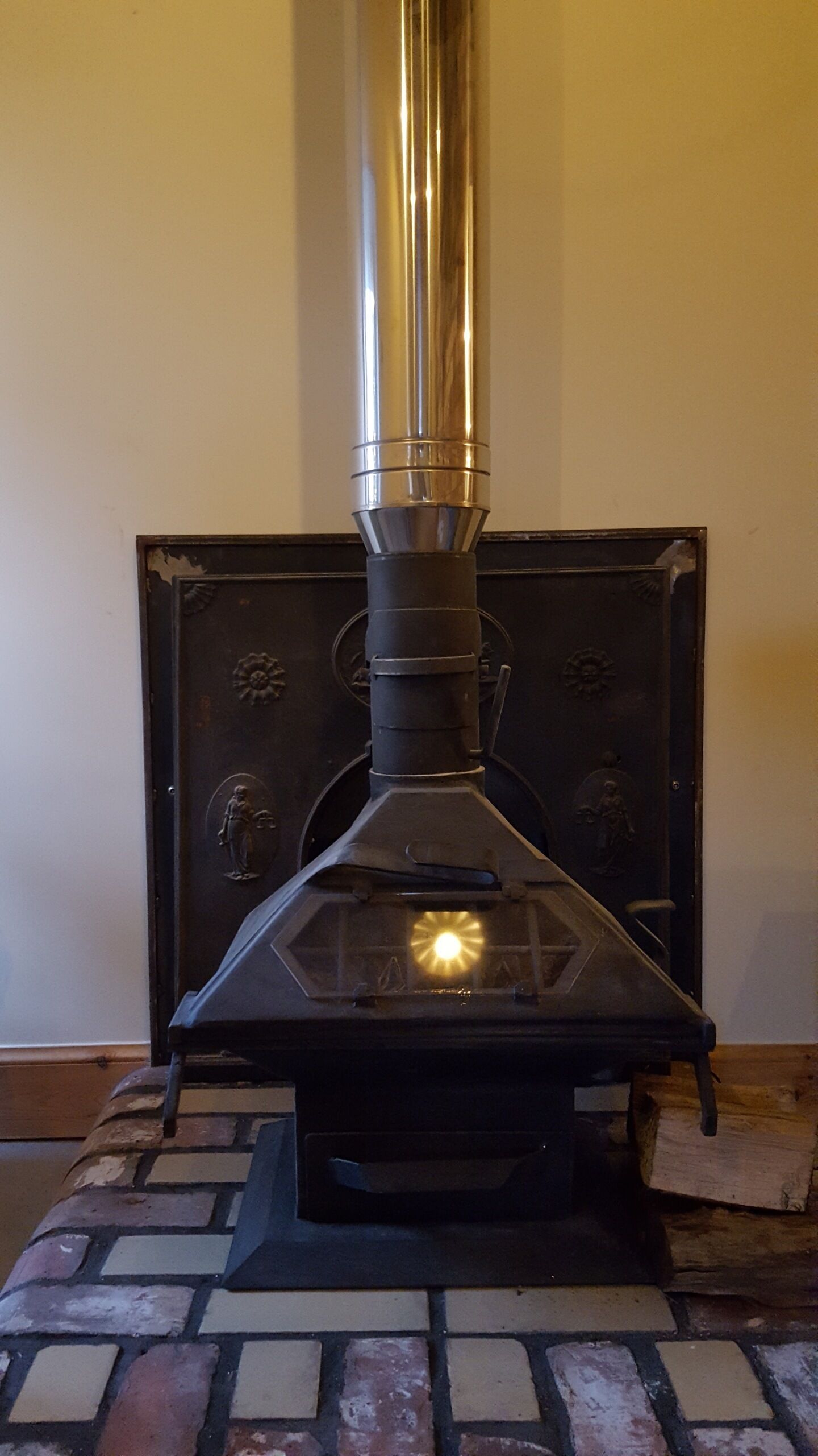 A wood-burning stove with a chimney, set on a tiled floor.