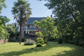 Une maison avec une pelouse bien entretenue, un palmier et un drapeau rouge.