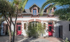 A two-story building with a red door and a balcony. - L'Oasis - Proche plage - Wifi - Jardin (Pornic)