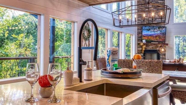 A spacious kitchen with a large island, a stone fireplace, and a view of the outdoors.