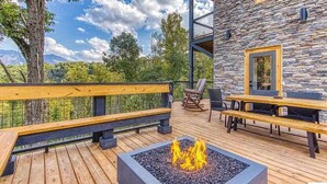 A deck with a fire pit, wooden benches, and outdoor seating.