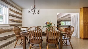 A dining area with a wooden table and chairs, a chandelier, and a log wall. - Mountain View: Hot tub and sauna, next to the river and horses (Kernville)