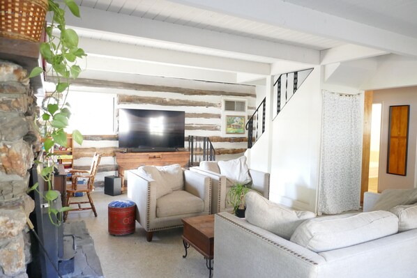 A living room with a television, sofas, a coffee table, and a staircase.