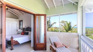 Una habitación con cama, zona de estar con vistas y balcón con vista al océano.