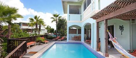 A pool area with a clear blue pool, wooden deck, and lounge chairs.