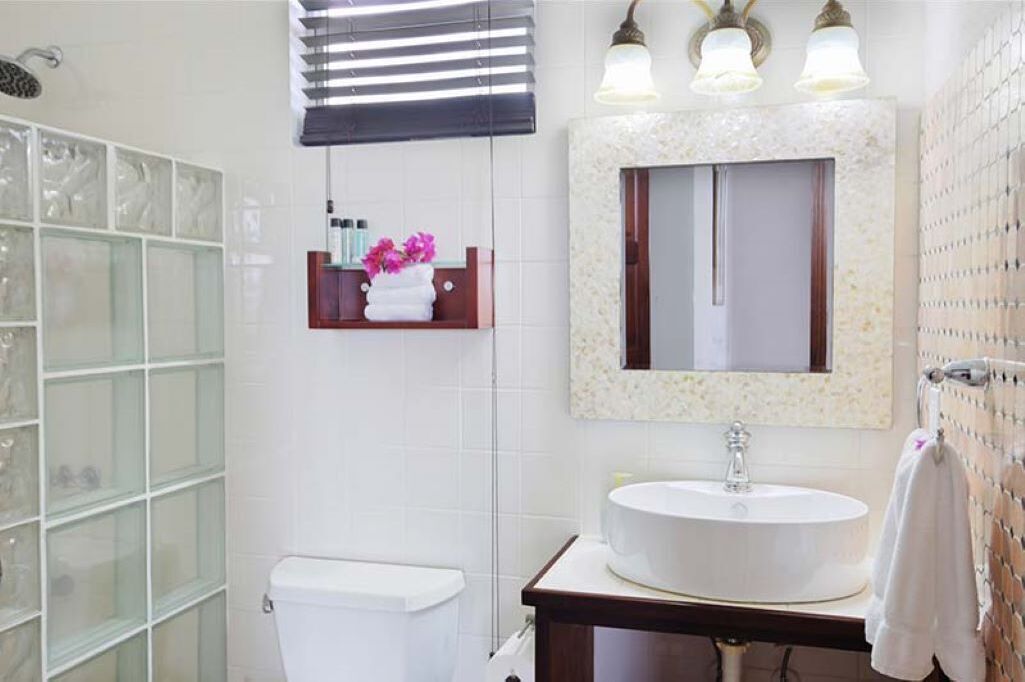 Une salle de bain avec une douche à parois de verre, des toilettes, un lavabo avec un miroir au-dessus et un porte-serviettes.