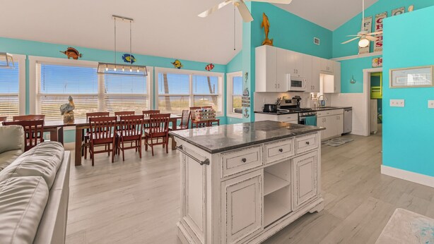 A spacious kitchen with white cabinetry, a central island, and a dining area with wooden chairs and a table.