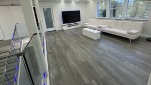 Una sala de estar moderna con un televisor de pantalla plana grande, un sofá blanco y una mesa de centro.