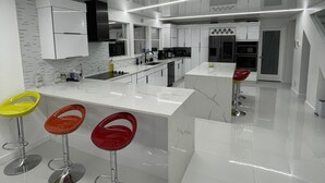 Una cocina moderna con armarios blancos, encimera de mármol y una isla central con taburetes.