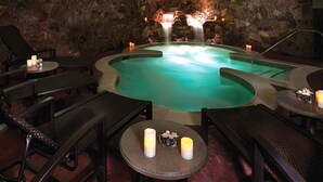 Un área de spa con jacuzzi, paredes de piedra y zonas de estar.