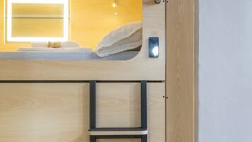 Una cama litera con cabecera de madera, una mesita de noche y una estantería empotrada.