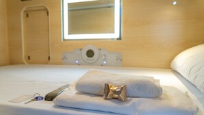 A neatly made bed with a rolled white towel and a small gold-colored item on top.