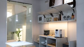 A modern kitchen with white cabinetry, a dining table with chairs, and a hanging light fixture.