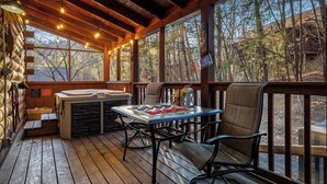 A wooden deck with a hot tub, table, and chairs, overlooking a forested area. - Timeless Tranquility-Screened Hot Tub-5 Min to Parkway-Pet Paradise-Dog Run! (Pigeon Forge)
