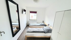 A small, bright room with two wooden beds, a large mirror, a window with a view, and a wardrobe. - Apartment Pottmensch near Centro with parking lot (Oberhausen)
