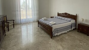 Une chambre à coucher avec un grand lit, une table de chevet en bois, une chaise et une armoire.