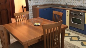 Une cuisine de taille réduite avec une table en bois, des chaises et un four encastré.