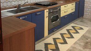 Une cuisine avec des armoires bleues, une hotte de cuisinière en acier inoxydable, un four encastré et un dosseret à motifs.