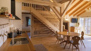 Een houten interieur met een keuken, eethoek en trap.