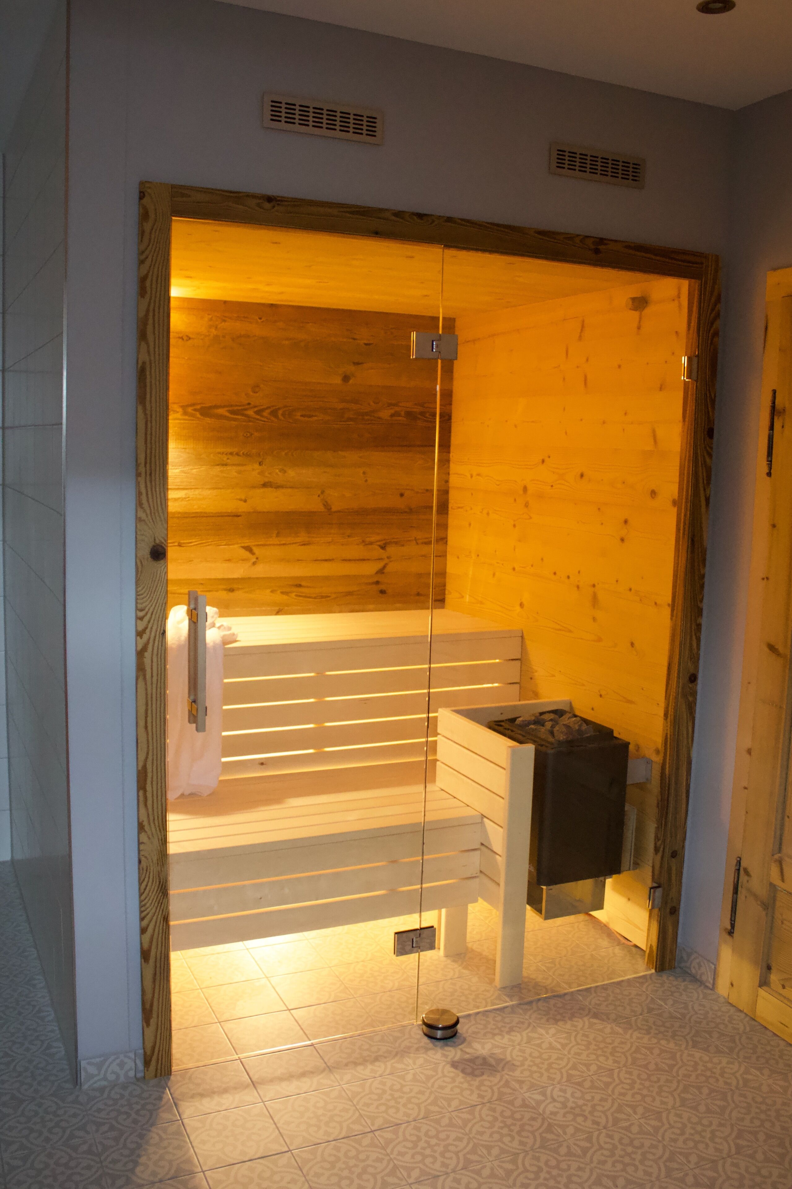 A sauna room with a wooden interior, a bench, and a towel rack.
