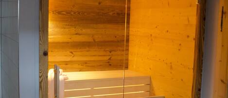 A sauna room with a wooden interior, a bench, and a towel rack.