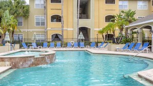 A swimming pool with blue lounge chairs and a small hot tub. - Newly renovated, free WIFI/PARKING, 10 min to the beach! (Clearwater)
