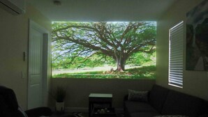 Una sala de estar con un ventanal que muestra un árbol y una zona cubierta de césped.