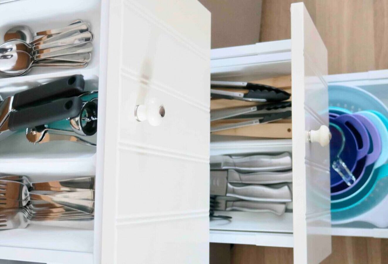 A drawer with utensils and a compartment containing a circular object.