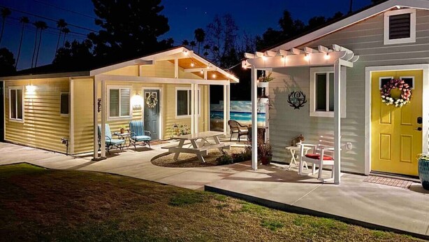 A row of mobile homes with attached porches, each with a table and chairs. - SoCal Daze, a Cozy Bungalow + Parking, Patio, BBQ (Pasadena)