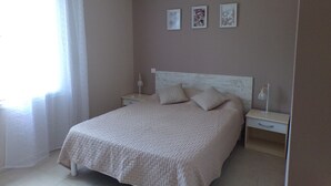 A bedroom with a bed, bedside tables, and a window with curtains.