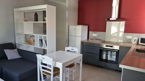 A compact kitchen with a dining area, a built-in bookshelf, and a red accent wall.