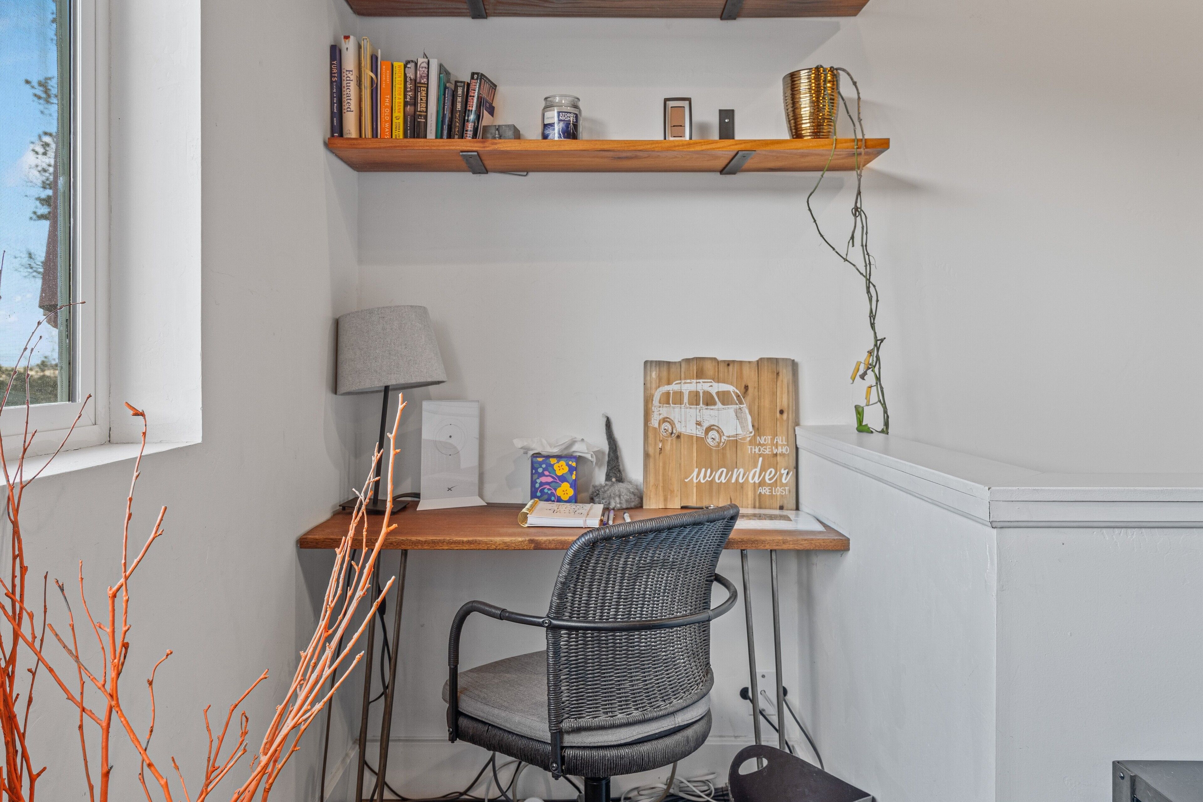 A workspace with a desk, chair, bookshelves, and a window.