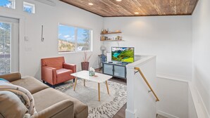En moderne stue med træloft, et fjernsyn og et hyggeligt opholdsområde.
