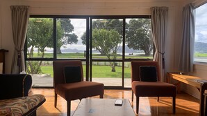 Una habitación con dos sillones mirando hacia un ventanal con vistas a un parque y montañas.