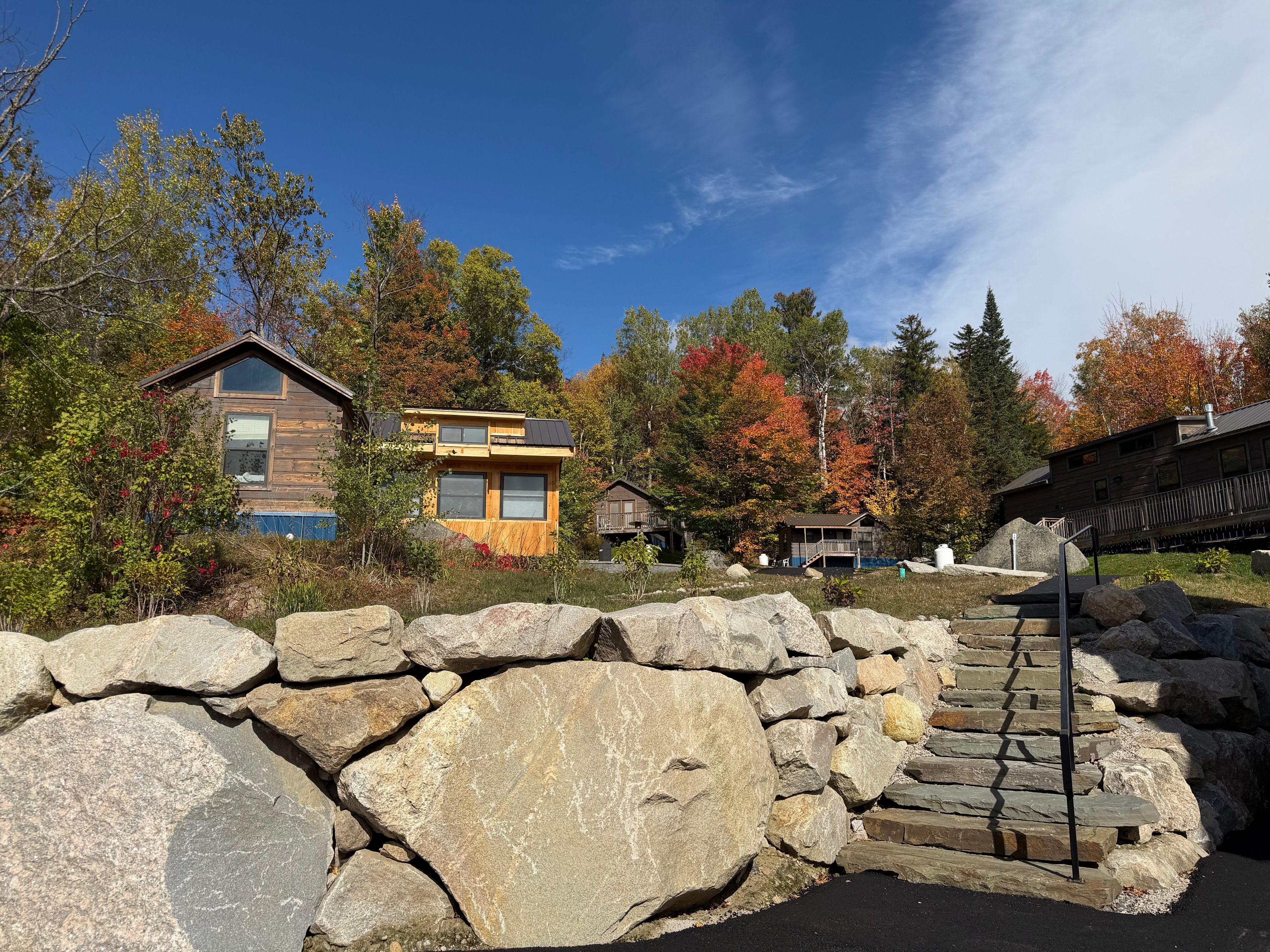 Un chalet rustique avec une entrée en pierre, entouré du feuillage automnal.