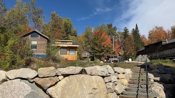 Un chalet rustique avec une entrée en pierre, entouré du feuillage automnal.