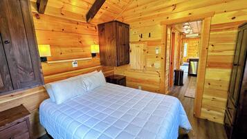 Een slaapkamer in een houten hutje, met een bed, houten wanden en een houten plafond.