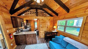 Interior d'una cabana amb cuina, zona de menjador i un sofà blau.