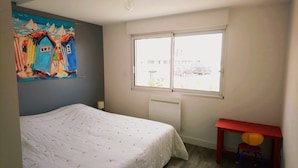 A bedroom with a bed, a window, a radiator, and a painting on the wall. - Ocean, beaches, kitesurfing, surfing 400 m away, ground-floor apartment with very large terrace  (Guidel)