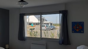 A hotel room with a large window, a bed, a painting on the wall, and a ceiling light. - Ocean, beaches, kitesurfing, surfing 400 m away, ground-floor apartment with very large terrace  (Guidel)