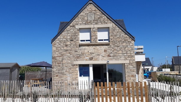 A stone house with a gabled roof, a wooden fence, and a clear blue sky. - Ocean, beaches, kitesurfing, surfing 400 m away, ground-floor apartment with very large terrace  (Guidel)
