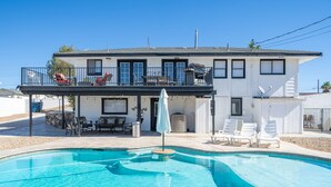 A two-story house with a swimming pool, outdoor furniture, and a covered patio area.