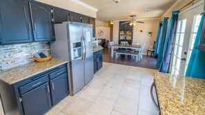 A modern kitchen with dark cabinets, granite countertops, and stainless steel appliances.